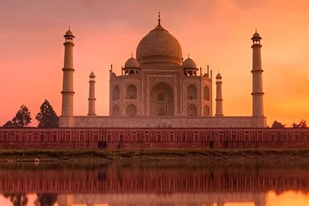 Early morning view of the Taj Mahal at sunrise, with soft golden light illuminating the white marble and peaceful surroundings, showcasing the beauty of the monument during the Sunrise Taj Mahal Tour.